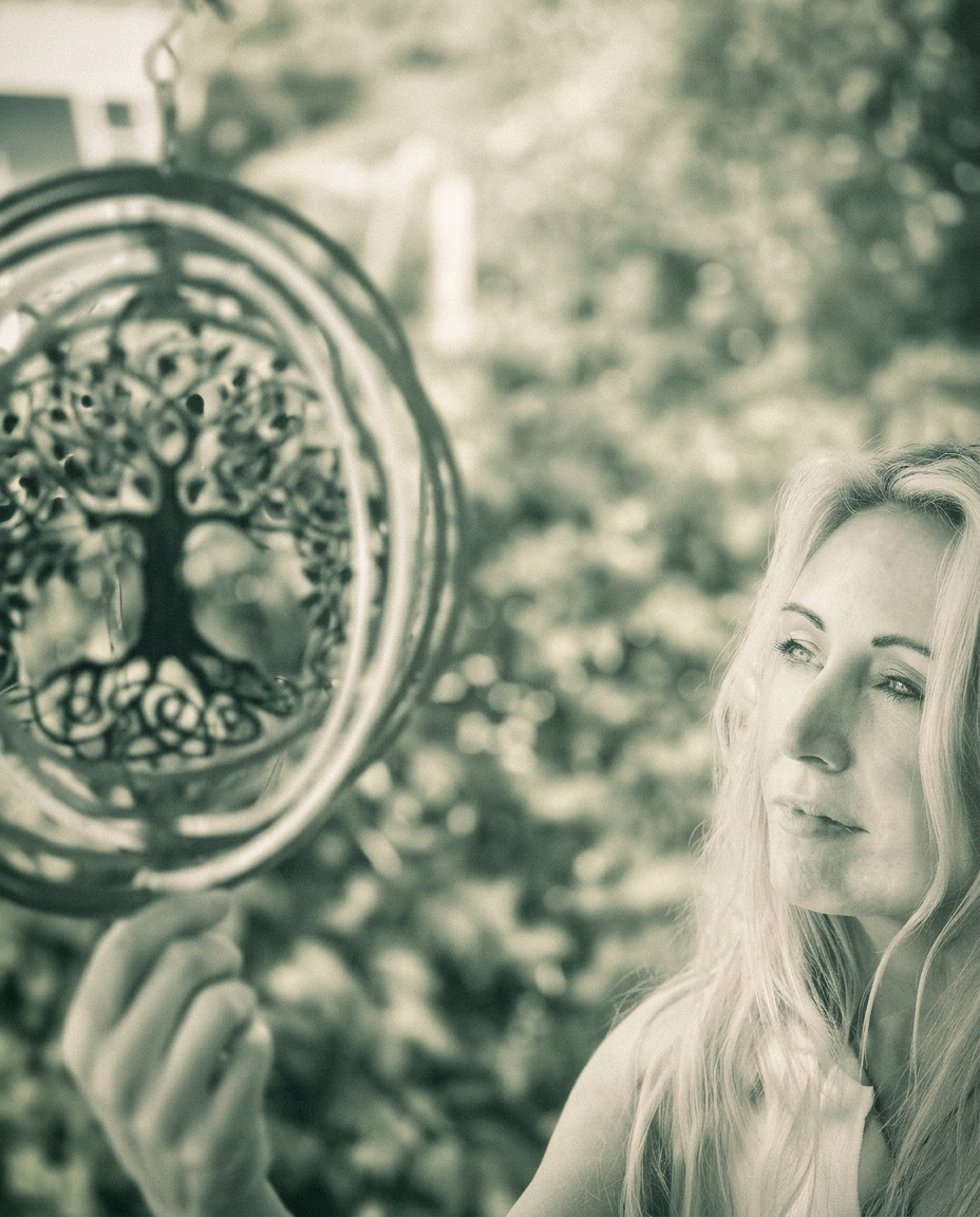 Anne Marie Sweeney holding a tree of life ornament in a sunlit garden